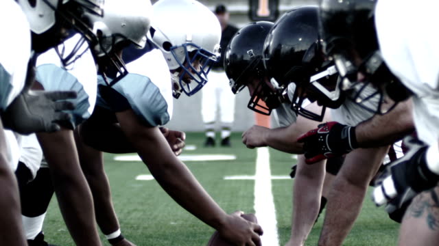 Close up of football players, linemen lining up and snapping the ball