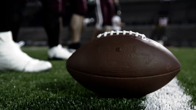 Close up of a football player's hand snapping the ball to the quarterback