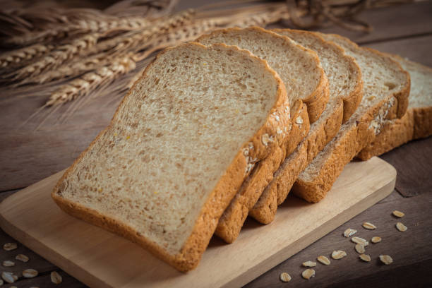 whole wheat bread on wooden plate - whole wheat imagens e fotografias de stock
