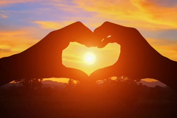 istock hand forming  a heart shape with  sunset  light and copy space for add text 684693424