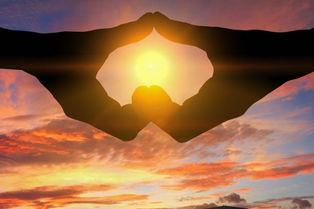 istock hand forming  a heart shape with  sunset  light and copy space for add text 684693480
