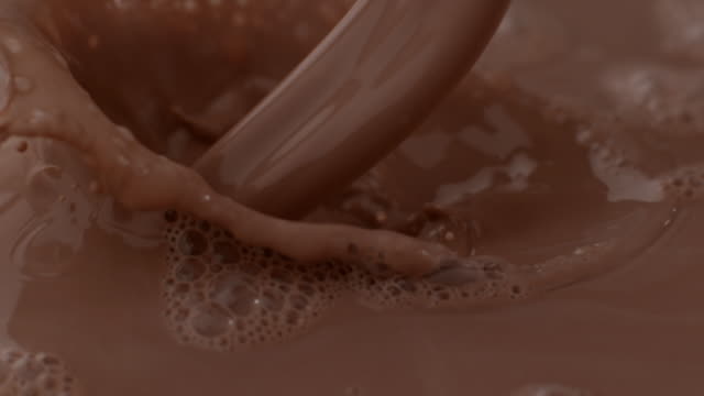 Chocolate milk pouring and splashing in slow motion