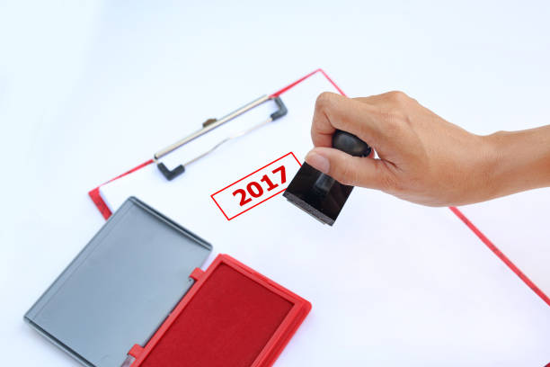 istock Close-up hand Stamping 2017 on paper sheet with red Ink pad(box) against white background. 684704062
