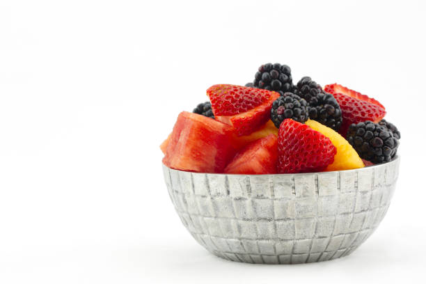 Metallic bowl filled with healthy, antioxidant fruits including sliced watermelon, cantaloupe, strawberries, and blackberries.