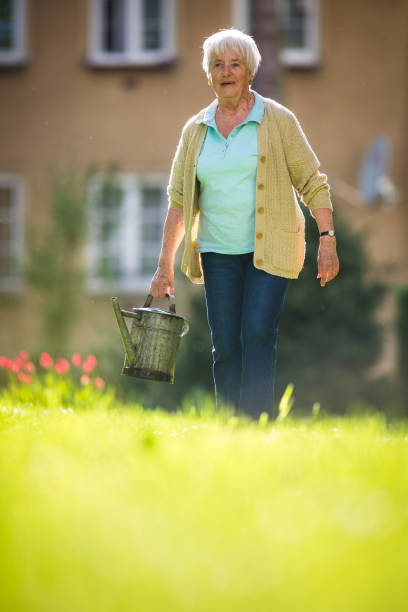 donna anziana che fa un po 'di giardinaggio nel suo grazioso giardino - manual worker glasses gardening domestic life foto e immagini stock