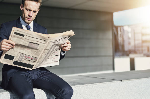 istock Man wearing suit sitting and reading newspaper 684803134