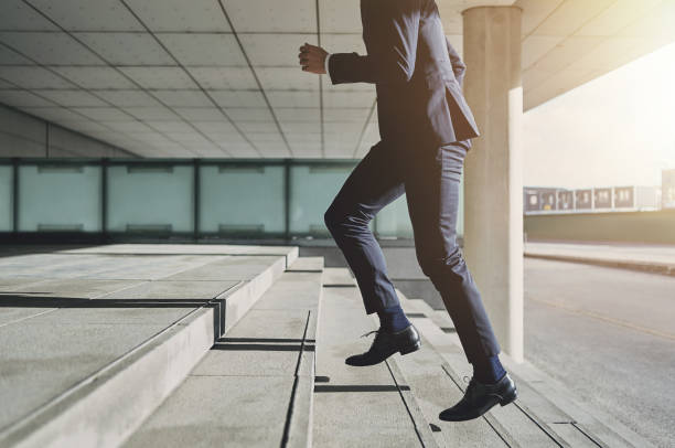 hombre vistiendo traje corre por las escaleras - escalón y escalera fotografías e imágenes de stock