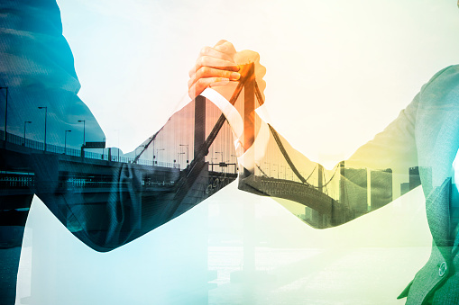 Double exposure of two business persons shaking hands and bridge skyline, relationship conceptual abstract