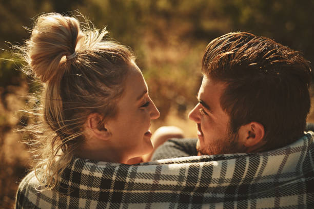 You make me fall in love all over again Shot of an affectionate couple wrapped in a blanket while spending time out in nature love me again stock pictures, royalty-free photos & images