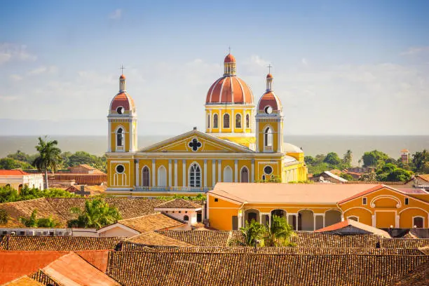 View towards the Cathedral of Granada, the famous Icon of the City of Grenada from above under a blue summer sky.  Lago de Nicaragua in the background, towards the horizon. Granada, Nicaragua, Central America.