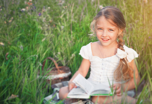 Cute little girl reading book on nature