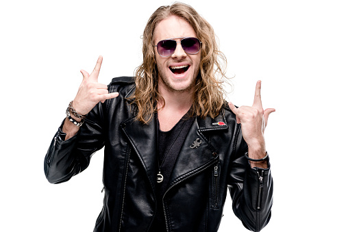 retrato de rocker guapo en chaqueta de cuero negro y gafas de sol que muestran signos de roca aislados en blanco, concepto de estrella de rock photo