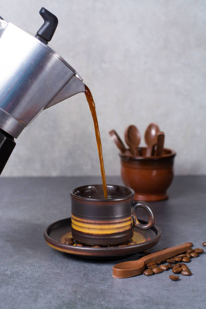 istock Black arabica coffee pouring from the coffee maker in cup and coffee beans on grey background with chocolade spoons 684830694