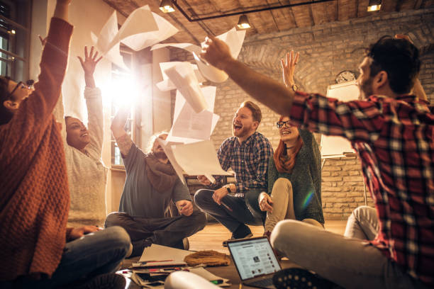 istock Happy start up team throwing papers in the air at casual office. 684834218