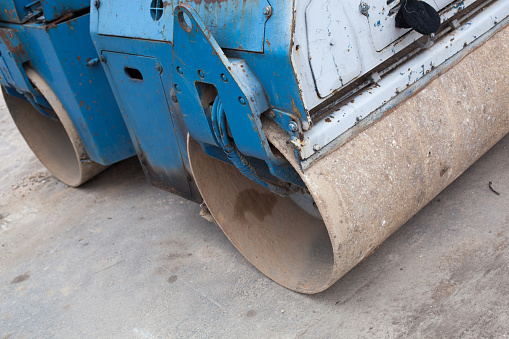 A large and powerful blue road roller on the construction site.
