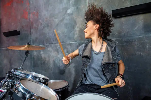 Photo of portrait of emotional woman playing drums in studio, drummer rock concept