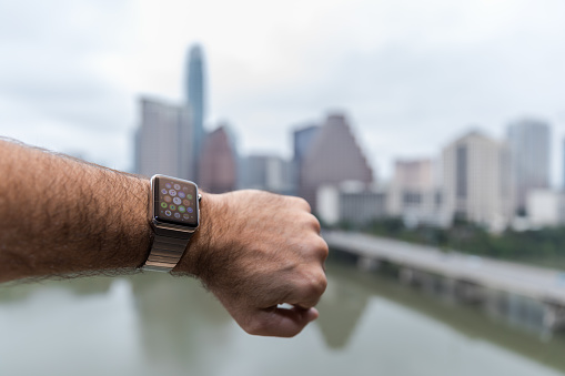 Man wearing and using a 42mm 316L Stainless Steel Apple Watch in Austin, Texas while looking at the cityscape. The Apple Watch became available April 24, 2015.