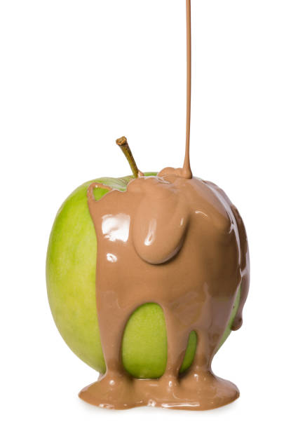 Green apple covered with flowing milk chocolate isolated on white background