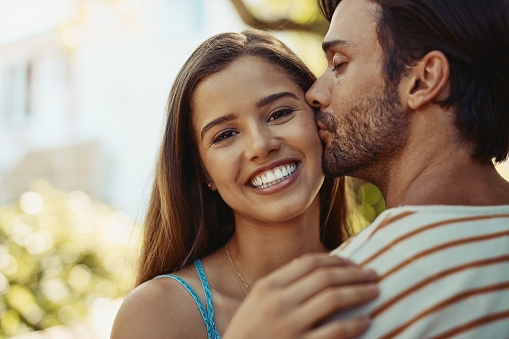 Portrait of an affectionate young couple sharing a kiss outside