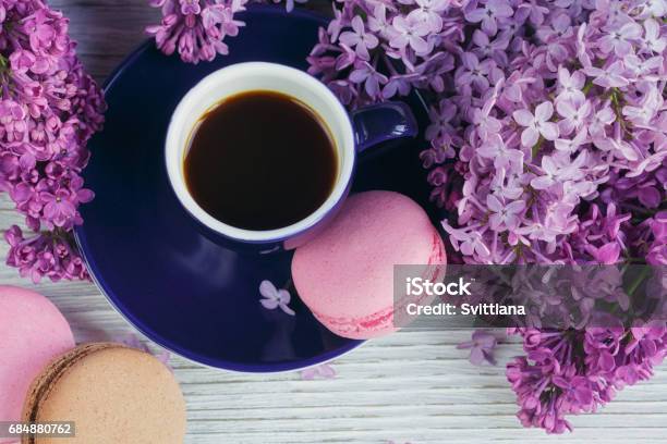 Cup Of Black Coffee Lilac Flowers And Sweet Pastel French Macaroons On Light Wooden Table Stock Photo - Download Image Now