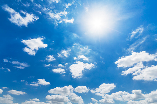 Bright sun with beautiful beams in a blue sky with some light clouds. Space for copy.