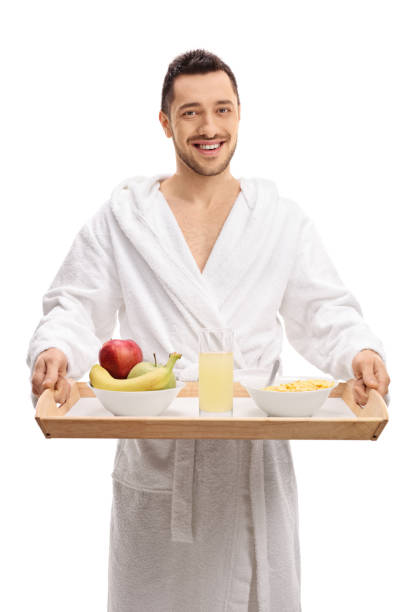 istock Young man in bathrobe holding tray with fruit, drink and cereal 684883910