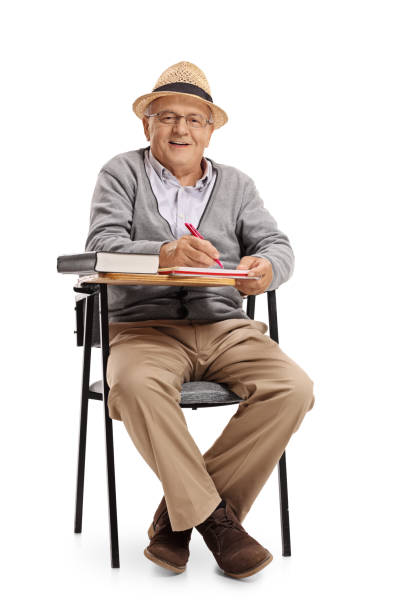istock Mature man in a school chair taking notes 684884084