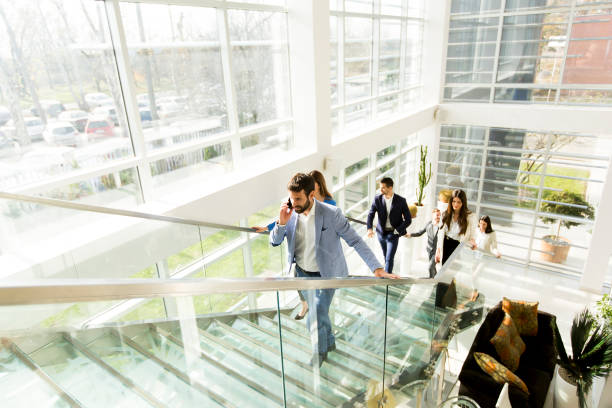 istock Young man with mobile phone on stairs in modern office 684886912
