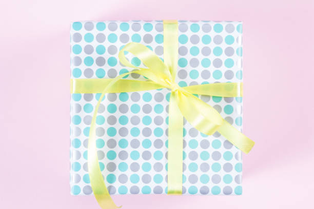 Gift box with yellow ribbon on pink background. View from above