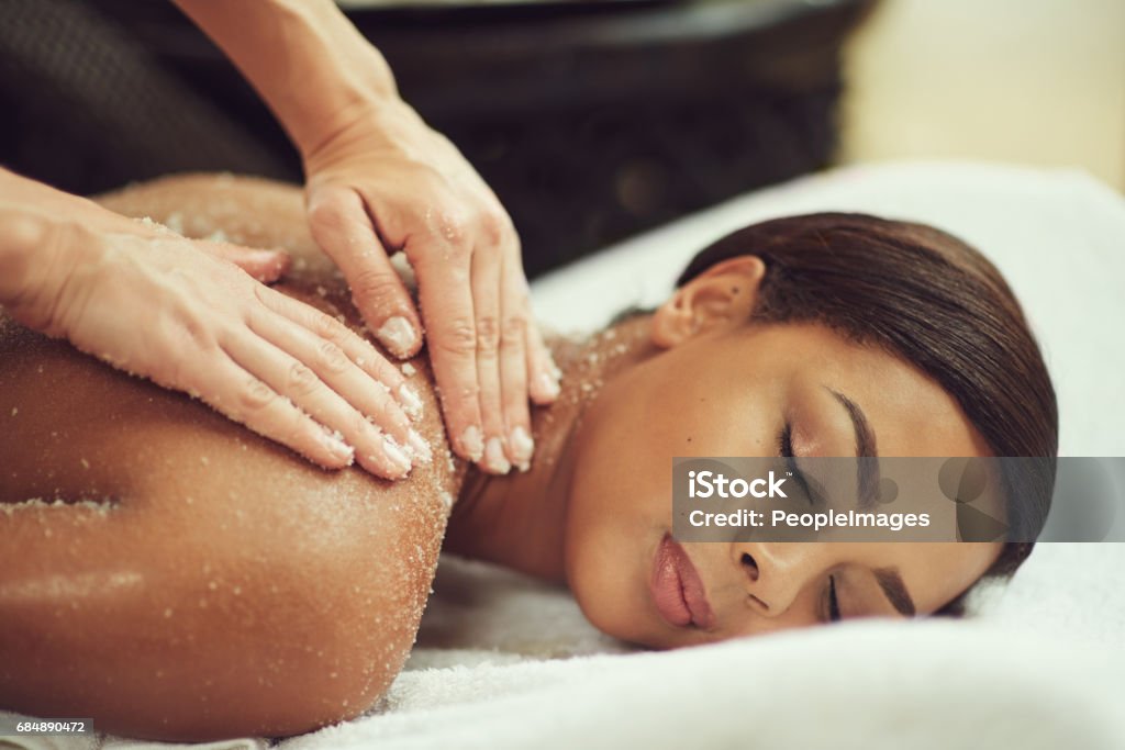 Exfoliation meets relaxation Shot of an attractive young woman getting an exfoliating treatment at the spa Exfoliation Stock Photo