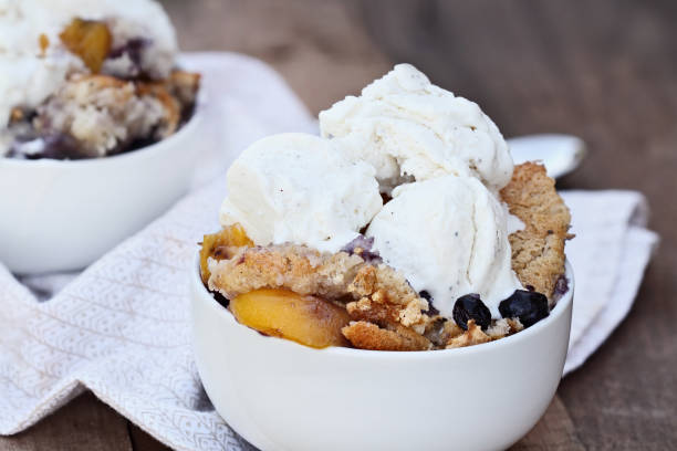 ciabattino di pesche e mirtilli con gelato - cobbler peach dessert fruit foto e immagini stock