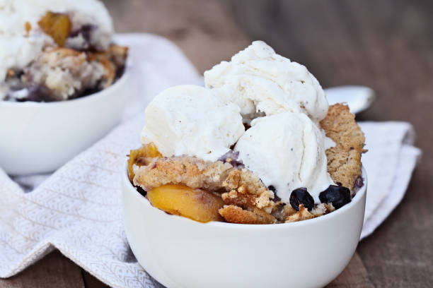 Peach and Blueberry Cobbler with Ice Cream Fresh peach and blueberry cobbler served with vanilla ice cream. Shallow depth of field with selective focus. cobbler dessert stock pictures, royalty-free photos & images