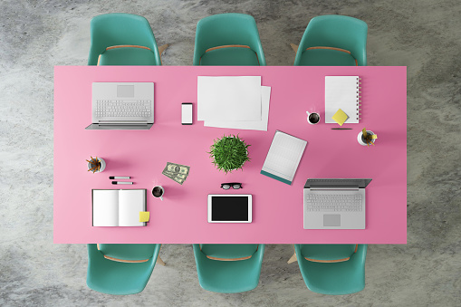 Knolling business desk teamwork meeting concept. Top view of a large colorful desk with pc monitor, laptop, papers, office equipment. Copy space template. Notepad, tablet, smartphone on top. Money, plant, lots of details with sticky notes. Table is vibrant pink