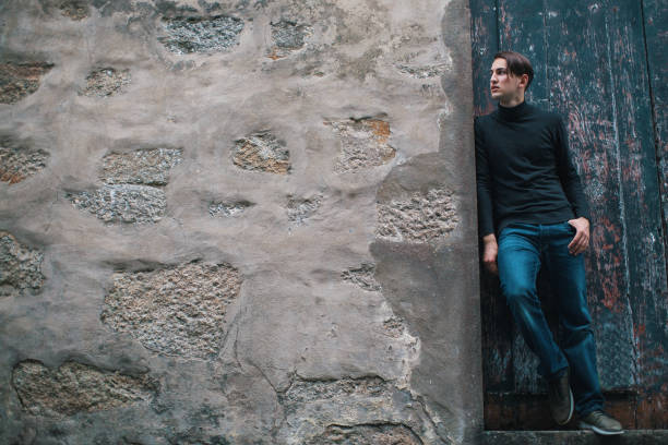 istock Handsome young man standing near old stone wall. Picture with space for text. 684939646