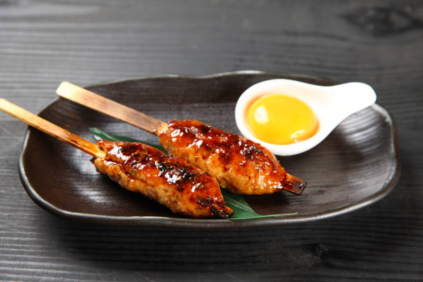 TSUKUNE Japanese chicken meatballs close up shot of TSUKUNE Japanese chicken meatballs with raw egg on black wooden backgrownd タレ stock pictures, royalty-free photos & images