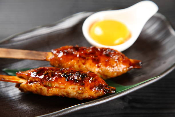 TSUKUNE Japanese chicken meatballs close up shot of TSUKUNE Japanese chicken meatballs with raw egg on black wooden backgrownd タレ stock pictures, royalty-free photos & images