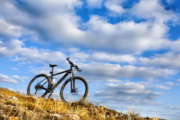 istock Black bicycle on hill with blue sky background 684947148