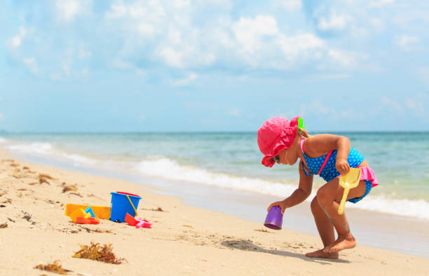 istock cute little girl play with sand on beach 684948212