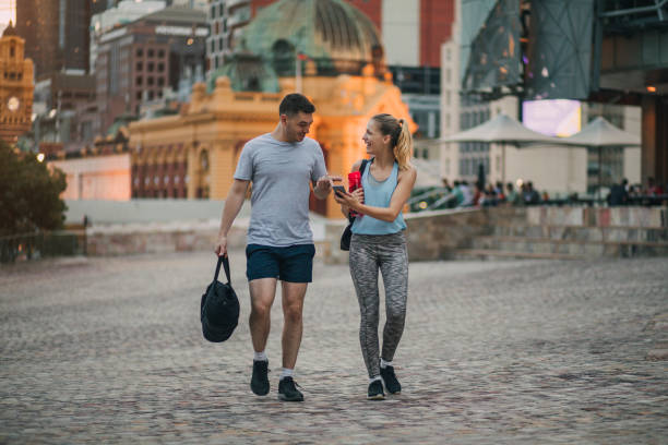 deux amis vêtus de vêtements de coussinage marchant dans le centre ville de melbourne - gym bag photos et images de collection