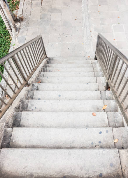 Old concrete staircase with the metal rail of the overpass bridge to the tiles pathway.