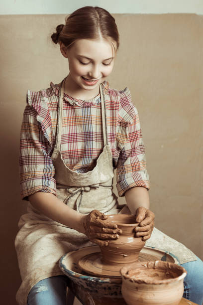 istock Front view of little girl making pottery on wheel at workshop 684993344