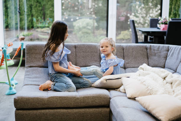 istock two sisters playing together on the big couch 685002552