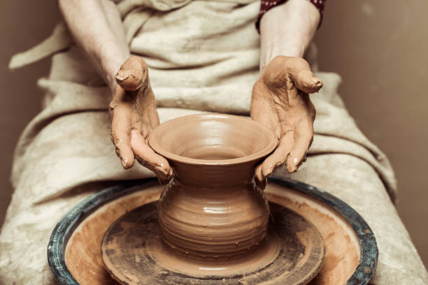 陶器の車輪で働く女性の手のクローズアップ - shaping clay ストックフォトと画像