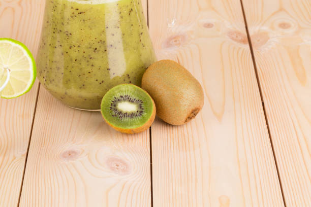 Kiwi juice and kiwi fruits. Located on the wooden desk. Close-up.