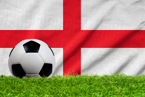Football on grass field with wave flag of England