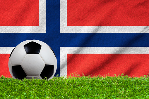 Football on grass field with wave flag of Norway