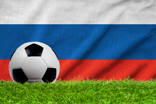 Football on grass field with wave flag of Russia