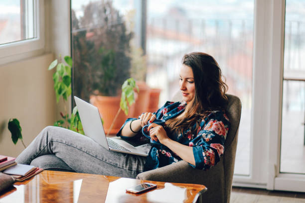 jeune femme travaillant à la maison à l’ordinateur portable - coffee table living room indoors comfortable photos et images de collection