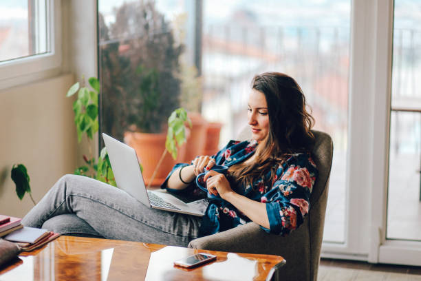 Vintage toned portrait of a young woman working at the table in the bright and beautiful apartment on the high floor in Belgrade, Serbia. She is wearing casual, everyday clothes and having a cup of coffee as well.