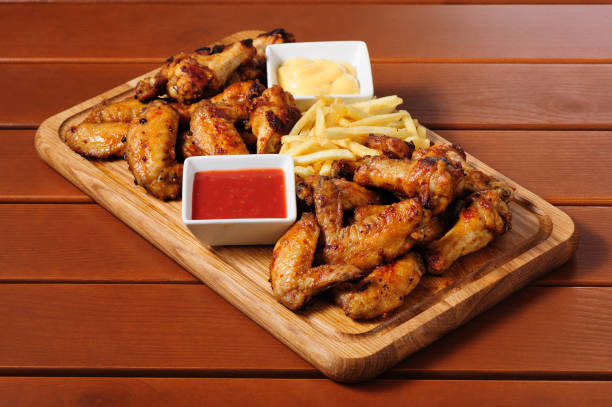 istock Big wooden board with grilled chicken winds 685071400